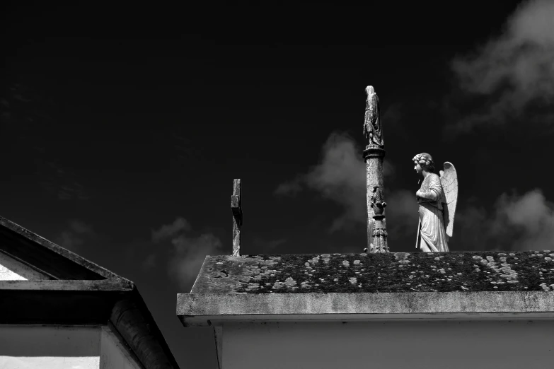 angel on the roof of a building and a black sky