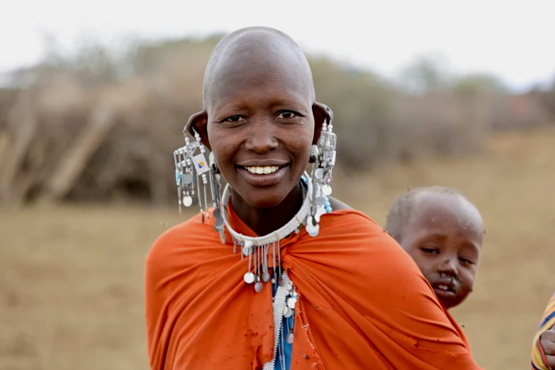 a woman in red shirt holding a baby and smiling