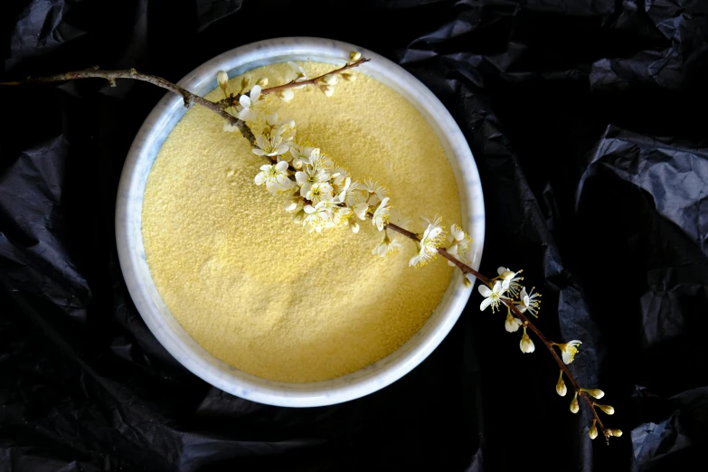 a bowl of yellow soup is on a dark background