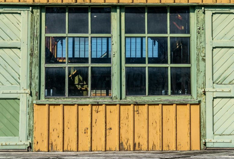 yellow and green windows of a building with wood siding