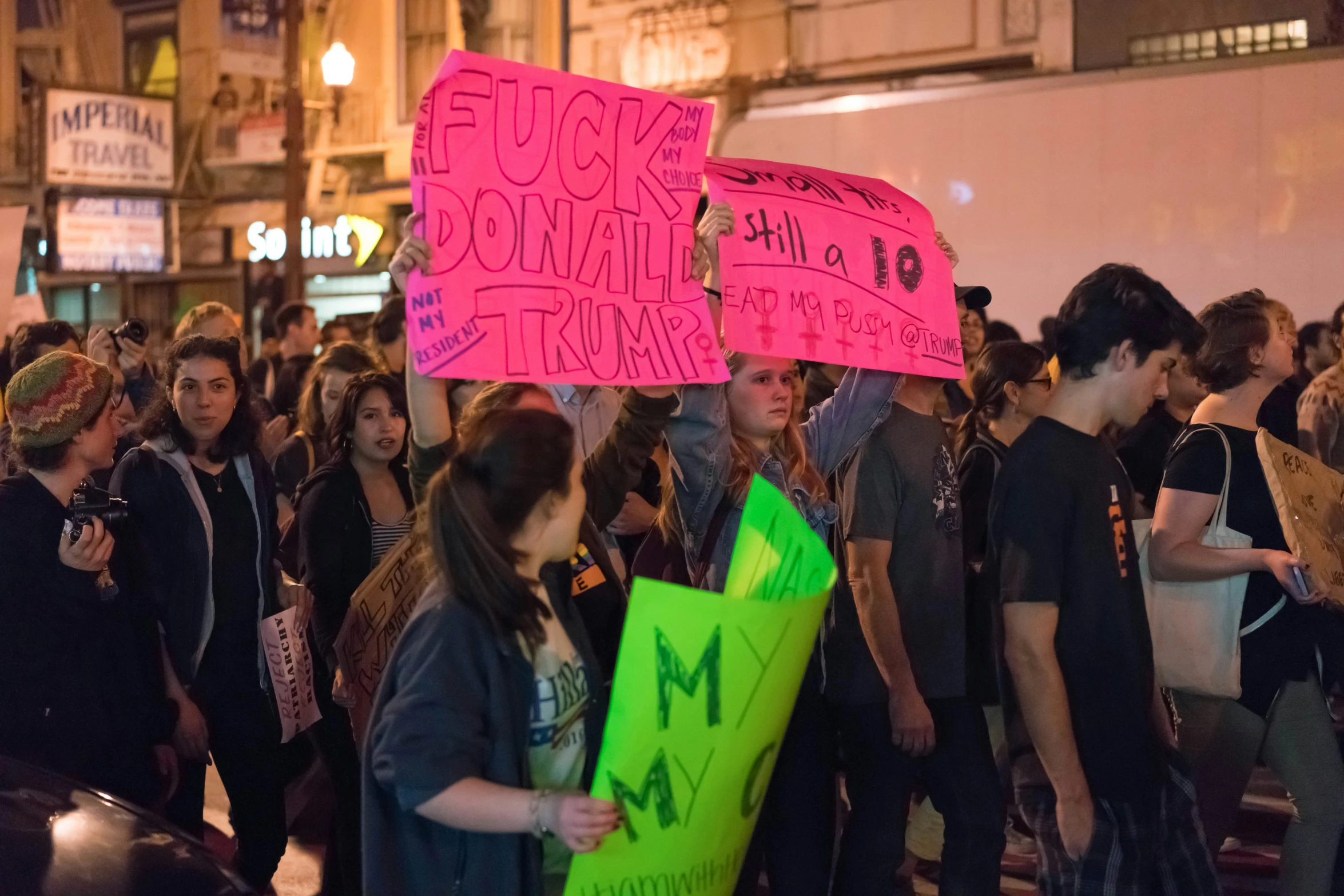 two people holding up neon pink signs in a crowd