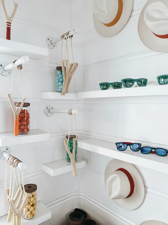 many hats hang on a shelf next to various sunglasses