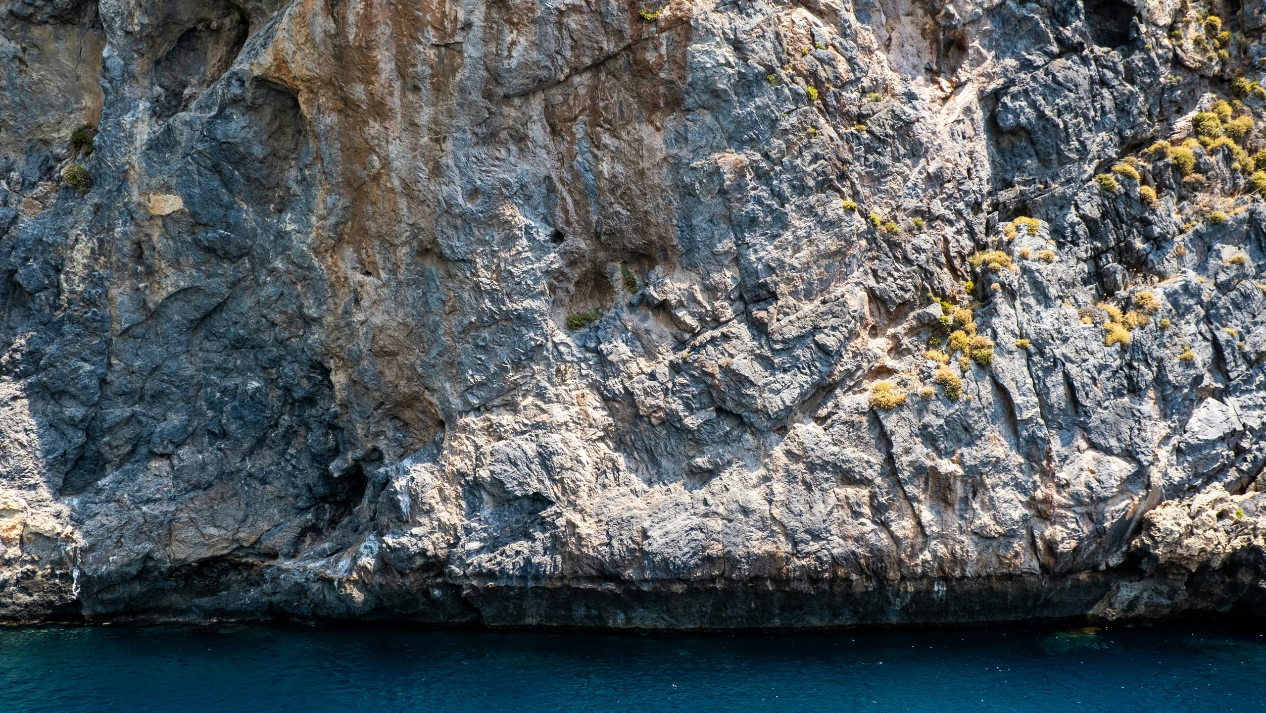 a cliff face is on the water by the shore