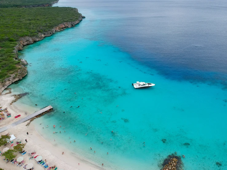 boats in the water near shore with beach chairs and umbrellas