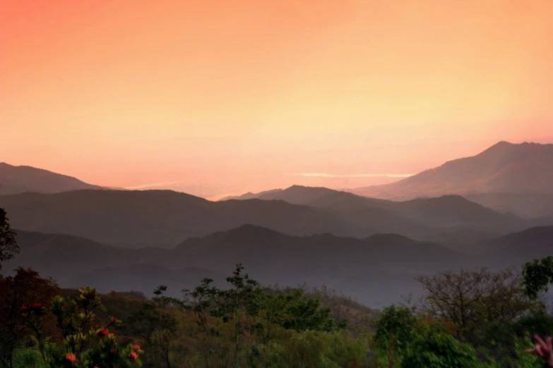 the sun setting over mountains and trees