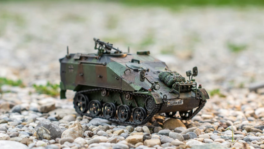 a toy army vehicle sitting on a gravel ground