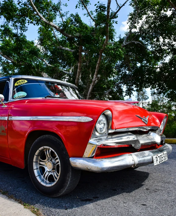 a old model red convertible parked in front of a tree