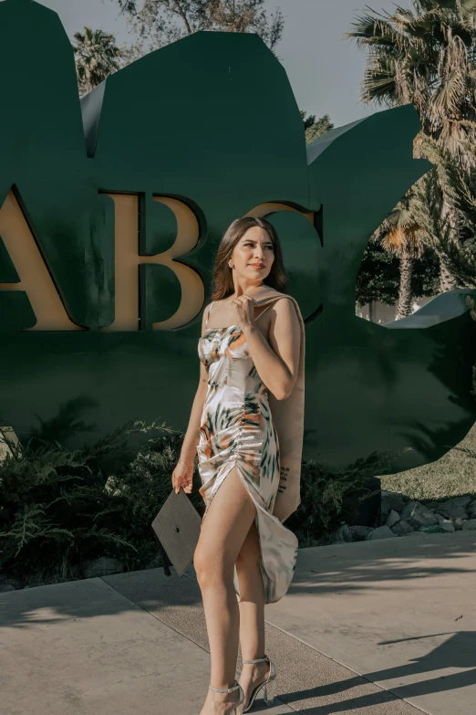 a young woman in an evening dress standing in front of a sign