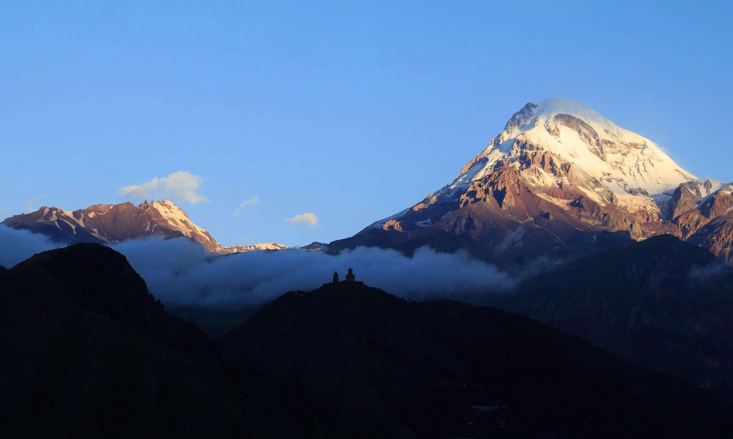 a mountain top with a bunch of clouds hovering around it