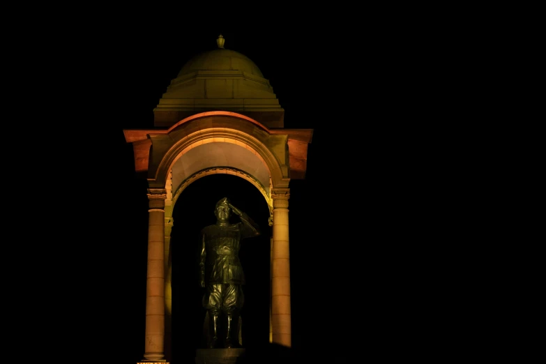 a tall tower with a statue next to it at night