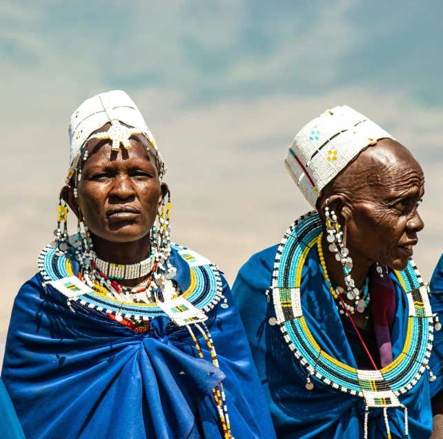 three masai people standing together looking at soing