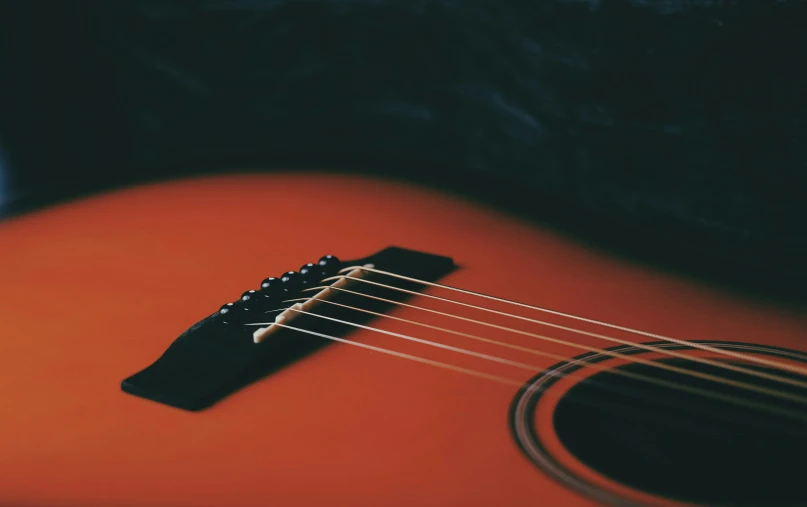 an orange guitar resting on the floor, possibly close up