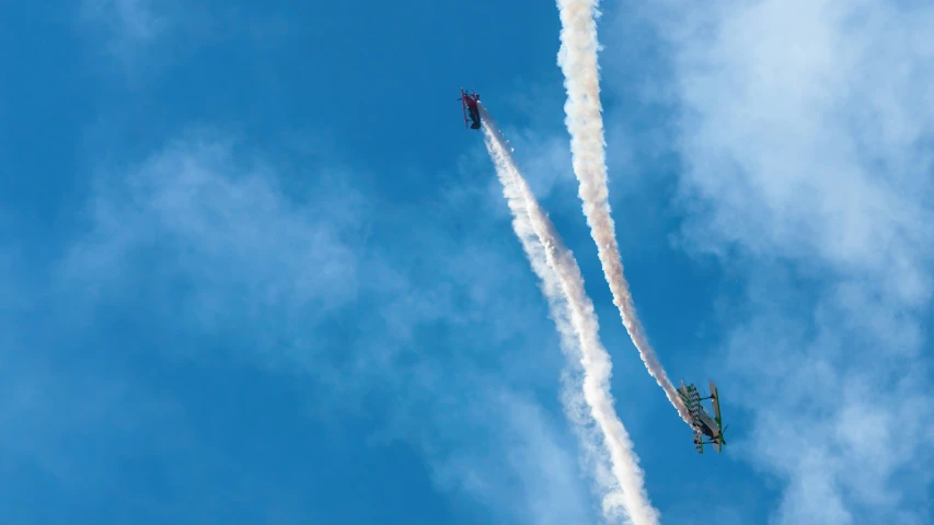 two fighter jets leaving trails while flying in the sky