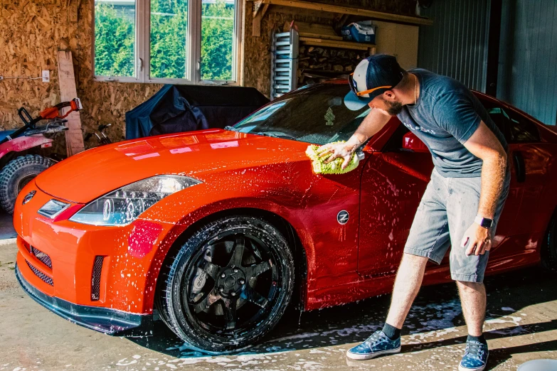 a man waxing a car's hood in his garage