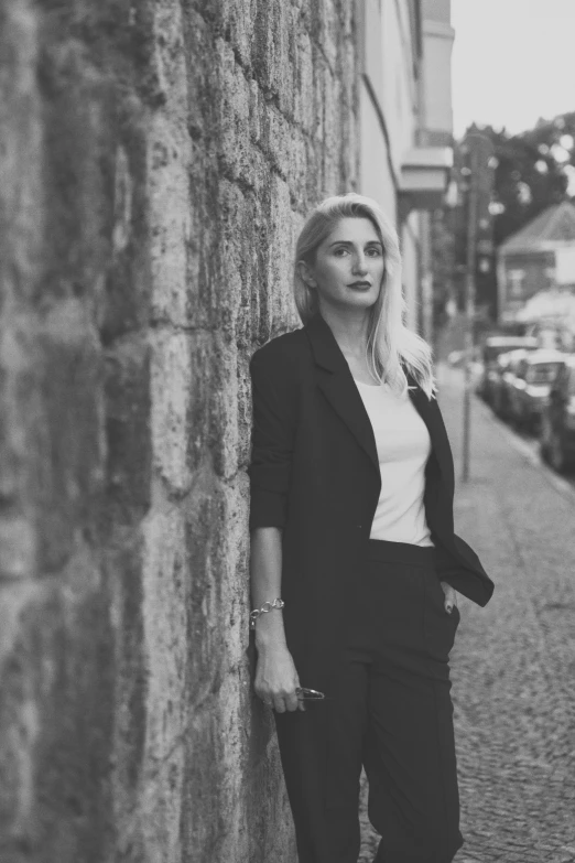 black and white po of woman leaning on a stone wall