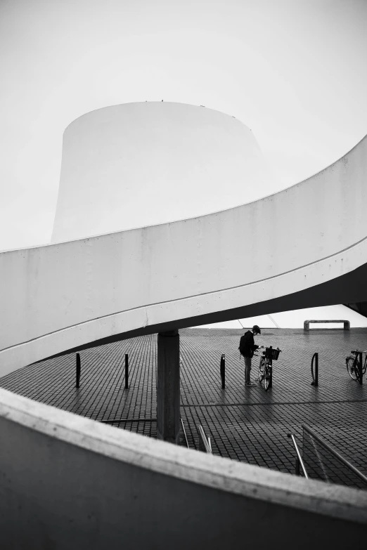 three people walking around inside a circular area with a large building in the background