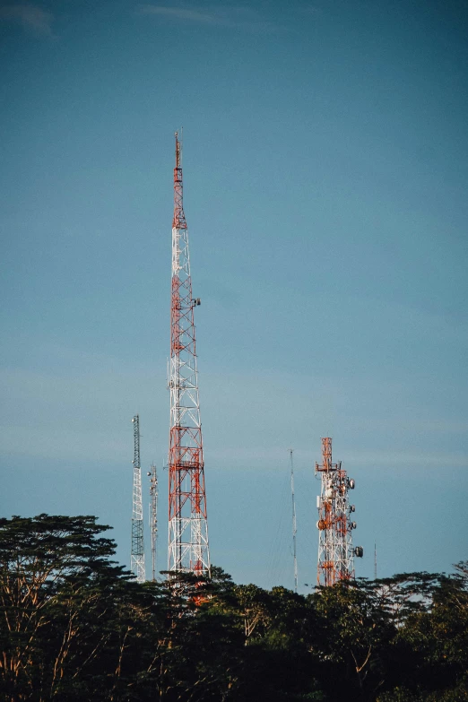 three cellular towers stand tall on the top of a hill