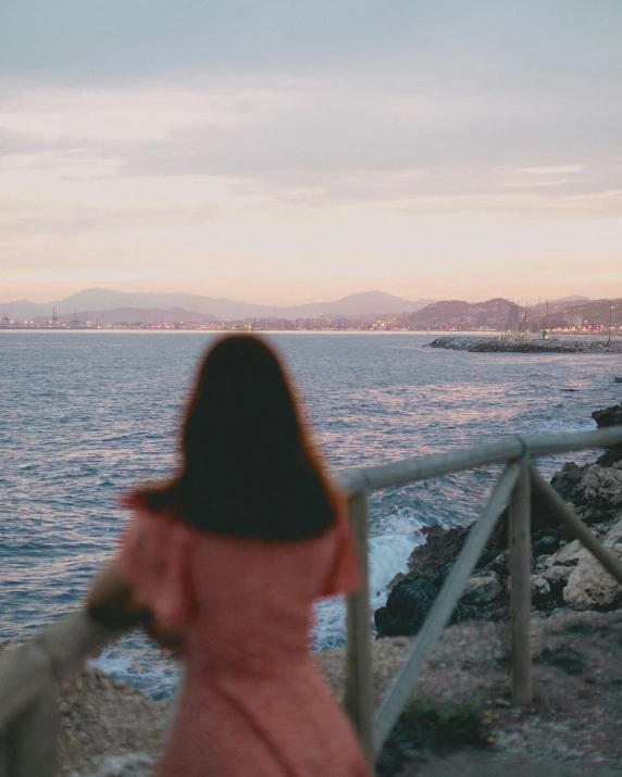 woman in a pink dress looks at the water