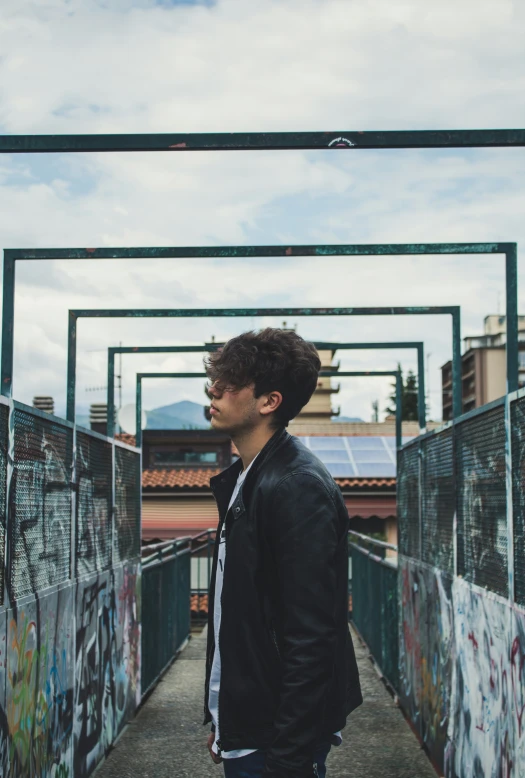 a man in black jacket next to a graffiti covered walkway