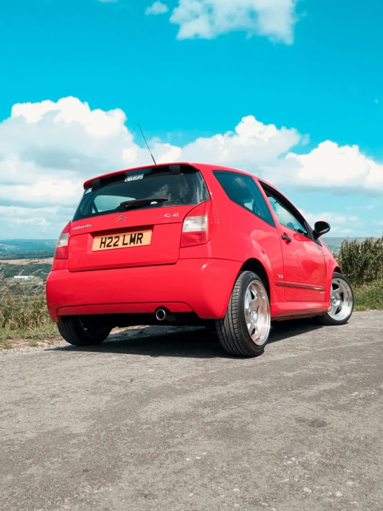 a car sits parked on a mountaintop under a blue cloudy sky