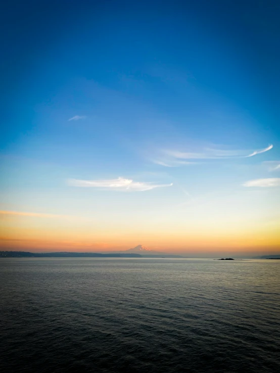 a boat out in the middle of the ocean at sunset