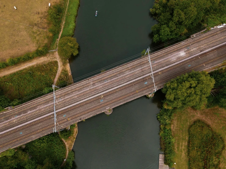 an aerial view shows the tracks and street crossing of a bridge over water