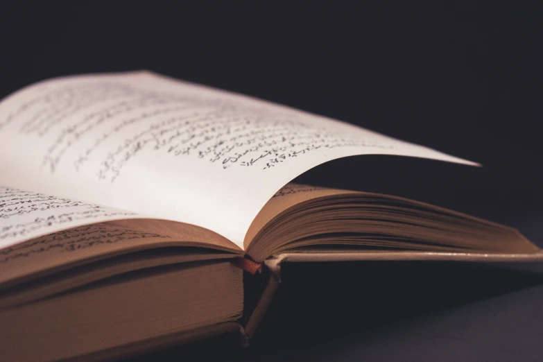 an open book on a table with a red ribbon on it