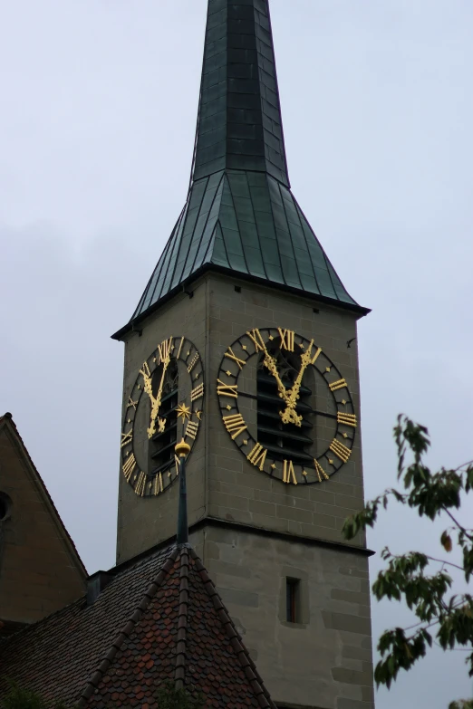 the tower of a church has gold and black clock faces