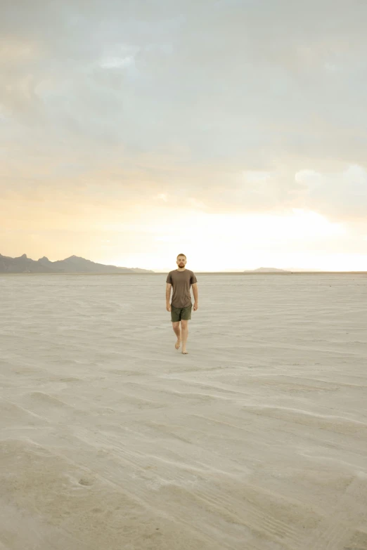 a man standing on the shore in an empty sand field