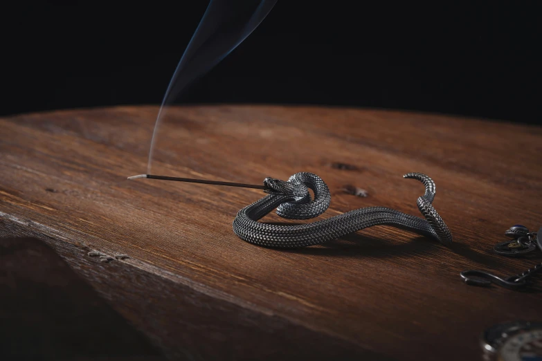 a snake made out of silver metal, holding a lighter