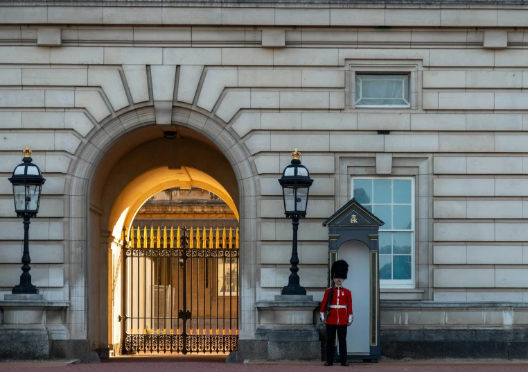 a guard in red uniform standing next to a white building