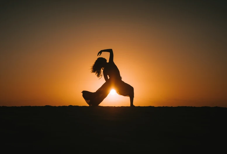 a person doing yoga in the desert as the sun sets