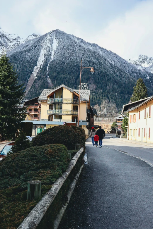 people walking on a road past a mountainside area