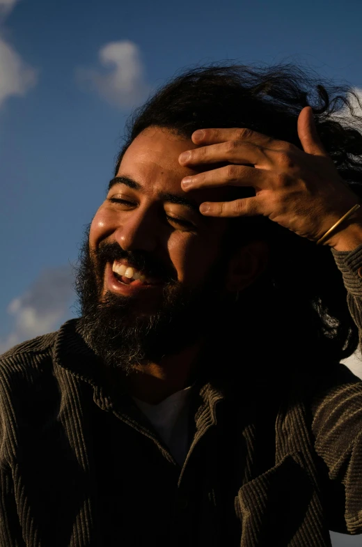 a man smiling and posing with his hands over his face