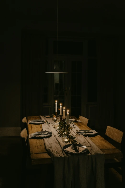 a christmas table setting with candles lit in the dark