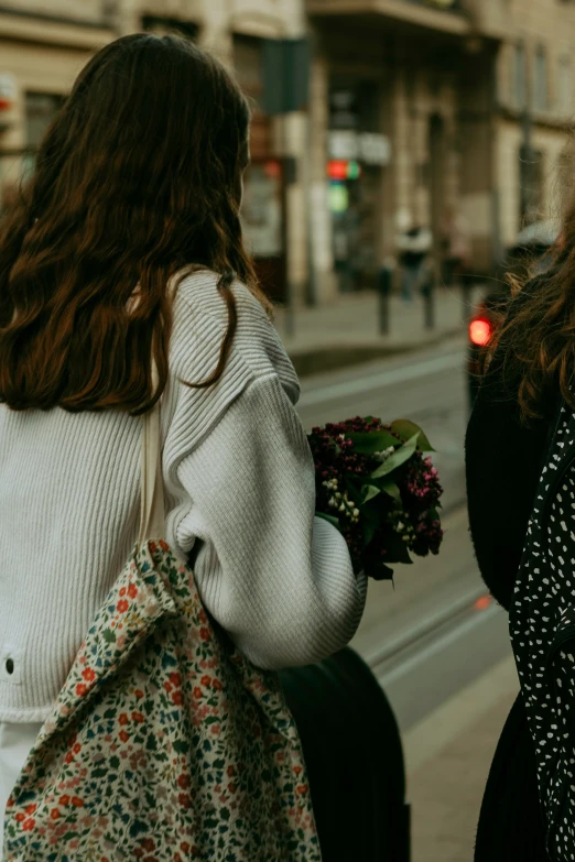 two women walking down a sidewalk with a hand bag in tow