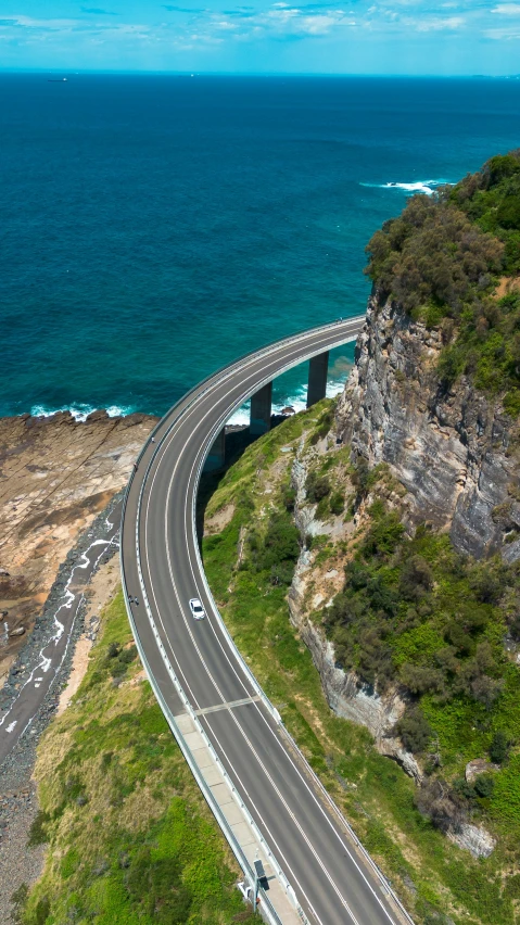 a road on a mountain with waves coming in from the ocean