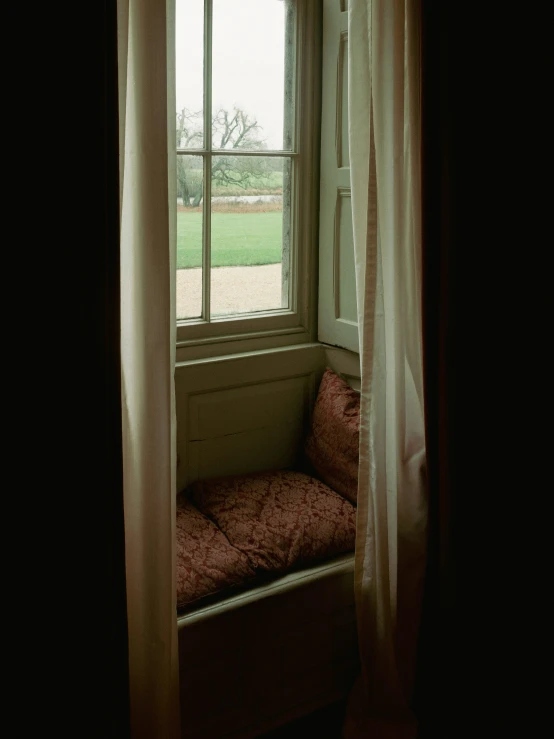 window with red curtains and a bench beside it