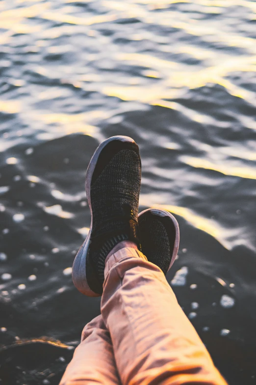 someone standing in front of water, their shoes in the water