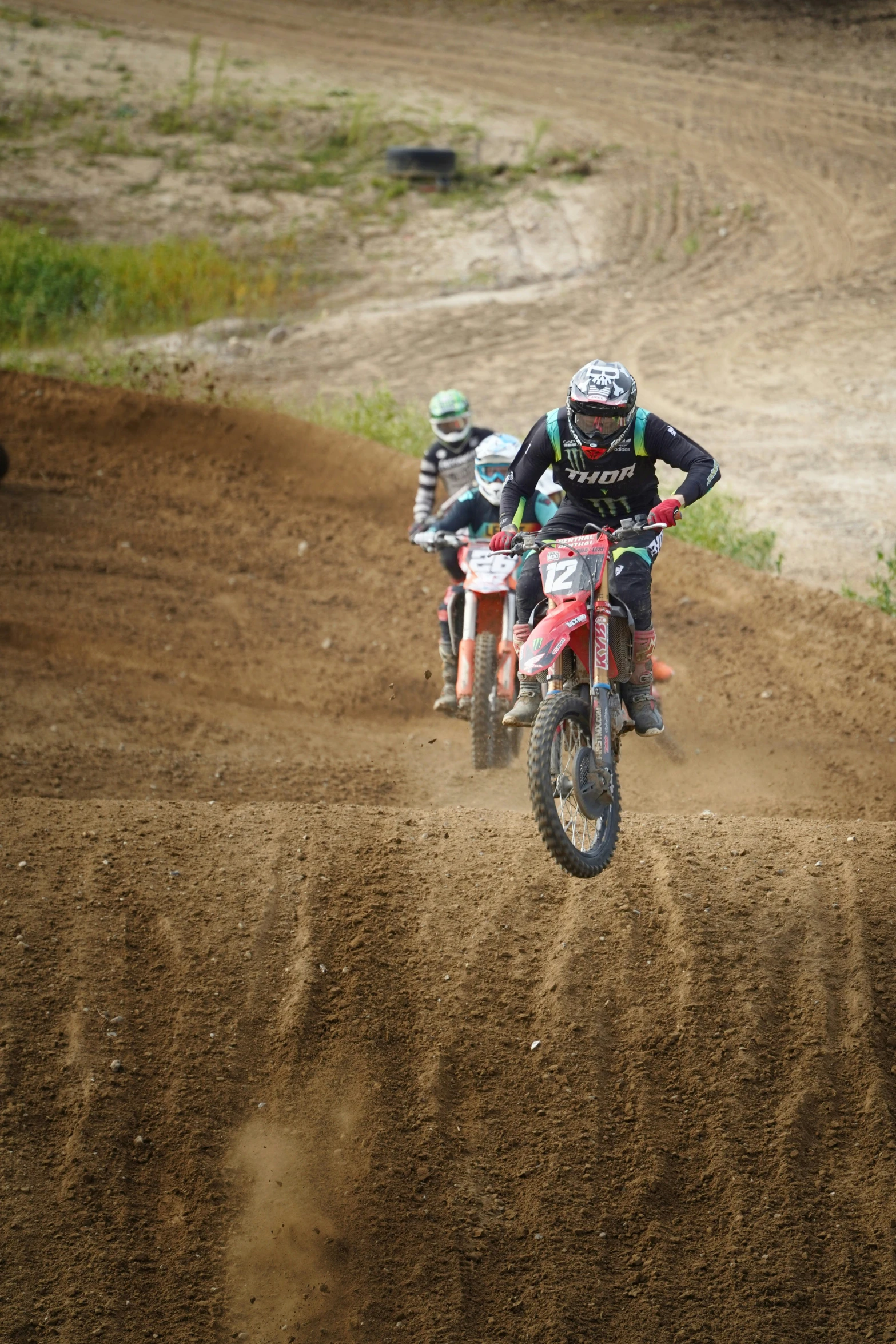 three young riders are racing on dirt bikes