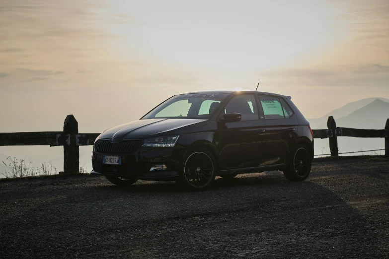 a black car on gravel next to a lake