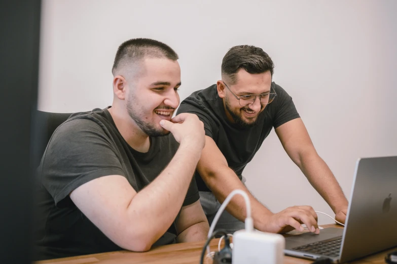 two men on their computers look at soing on the screen