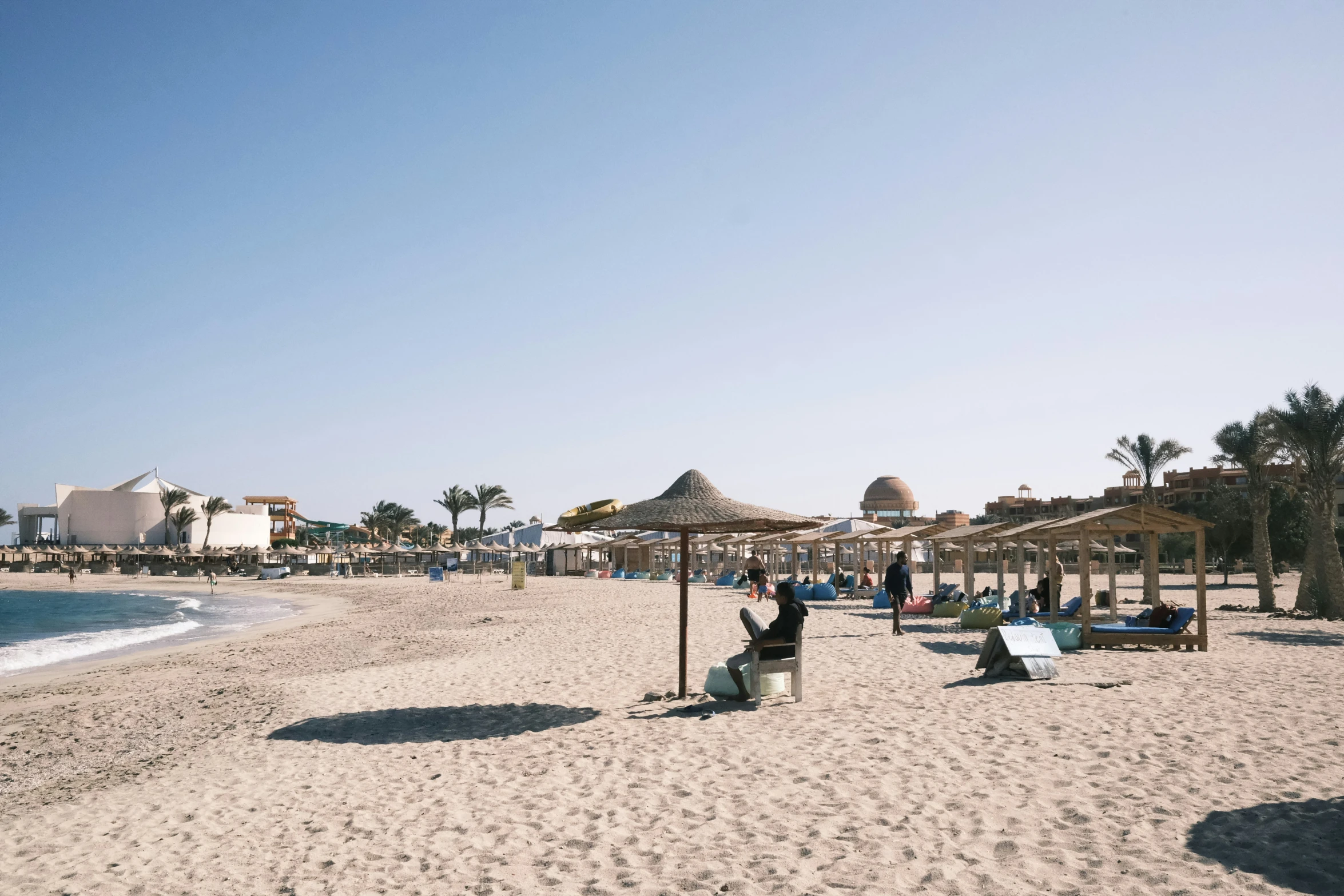 a beach with several people walking on the sand