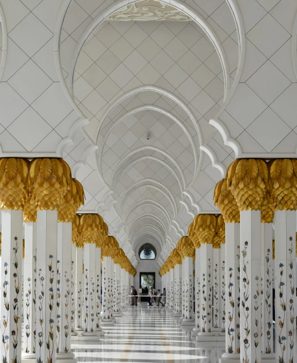 a hallway with a white and gold ceiling with columns