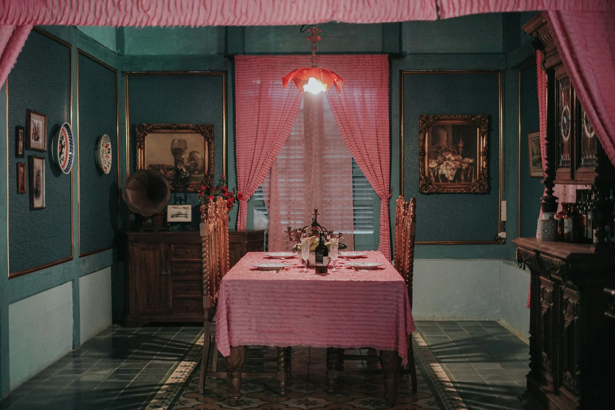 a pink table cloth sits in front of a dining room window with pink curtains