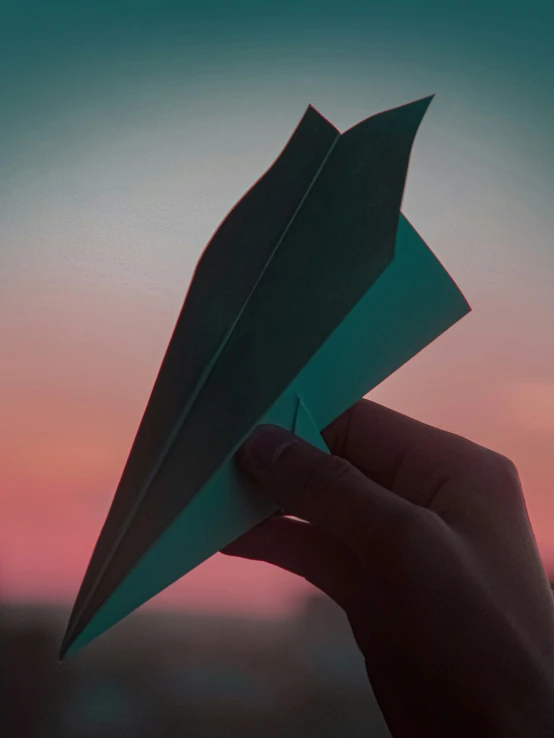 a hand is holding a paper plane and it looks like it could be about to launch