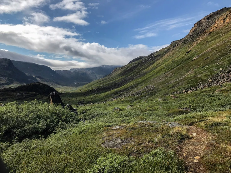 the mountains of a valley under a partly cloudy sky