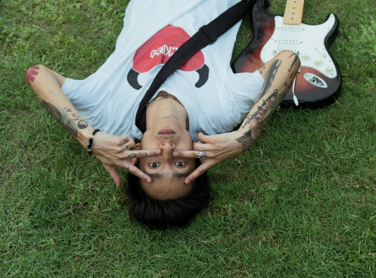 woman holding up guitar straps to her face laying on grass