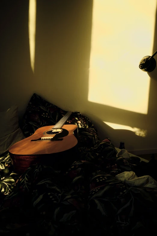 a guitar laying in a bedroom near a wall