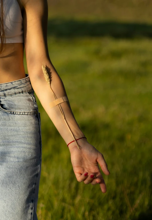 woman with tiny tattoo holding hand out in grassy field